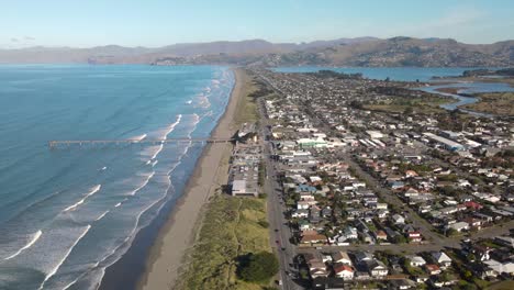 Long-sandy-beach-and-popular-New-Brighton-Pier-in-Christchurch,-beautiful-mountain-landscape-on-horizon