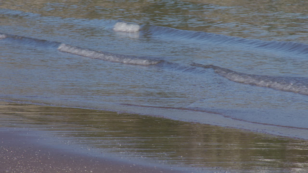 Close up shot of waves rippling onto new quay beach at new quay bay