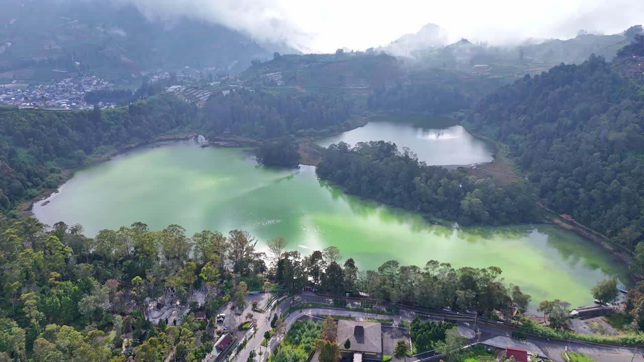 Panoramic aerial shot of a tropical highland lake surrounded by dense forest and misty mountains. Serene natural landscape perfect for travel, nature, and environmental themes