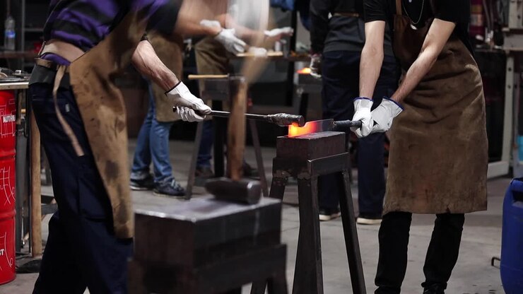 Blacksmiths making iron instrument with hammer