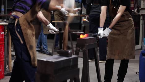 blacksmiths making iron instrument with hammer