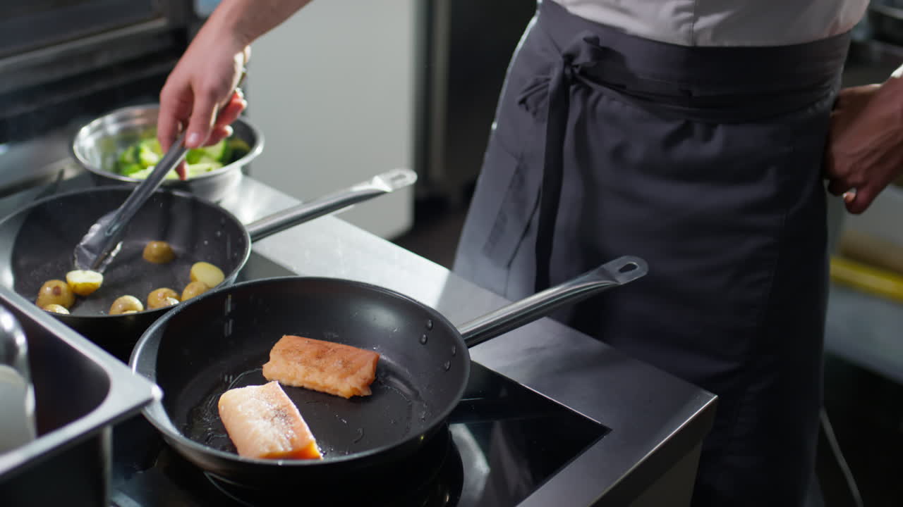 Chef che frigge patate novelle e pesce