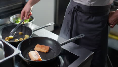 chef frying baby potato and fish