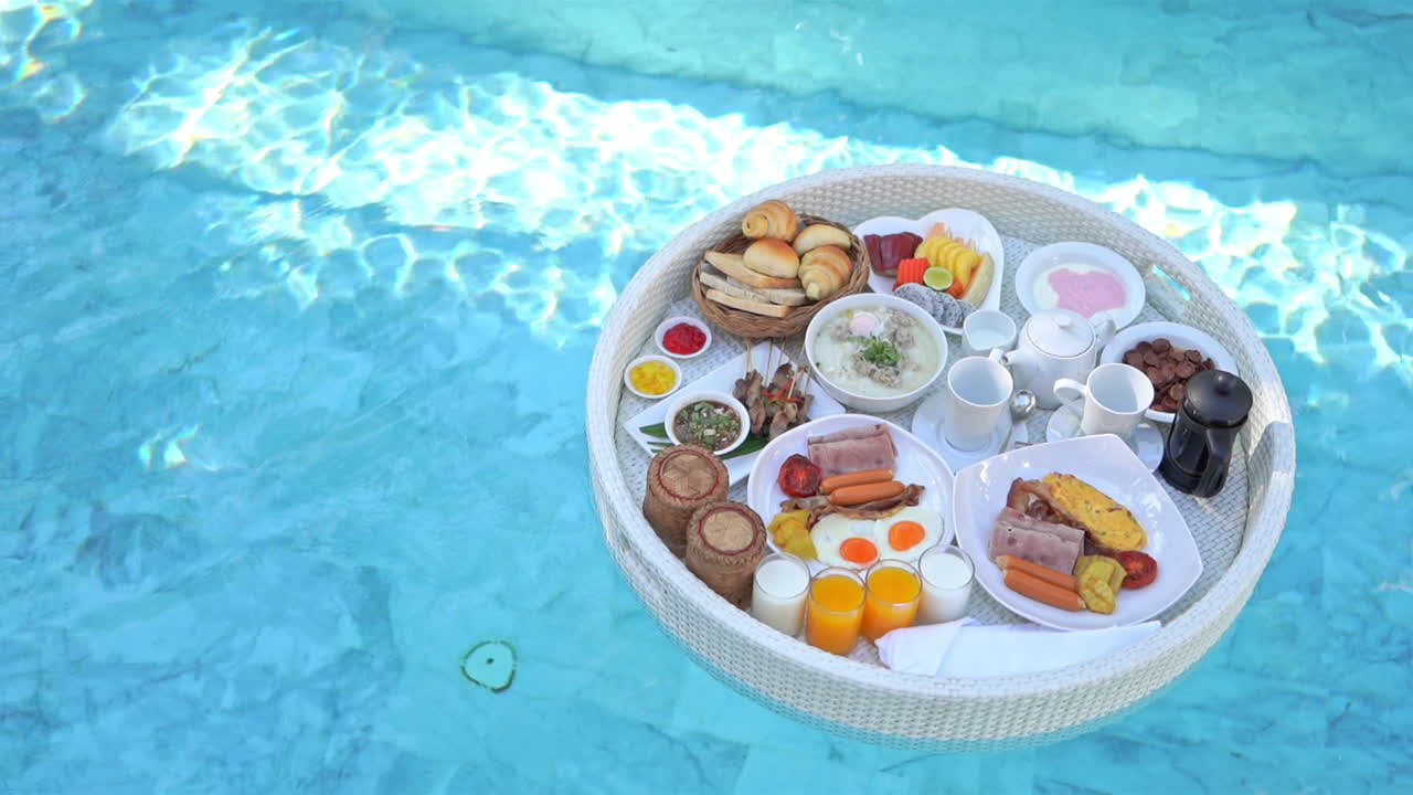 A floating breakfast tray, which is an exotic attraction in a luxury hotel, floating on the surface of pool water with no people in the shot