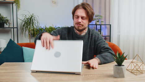 angry caucasian man use laptop surprised by bad news fortune loss game fail lottery results at home