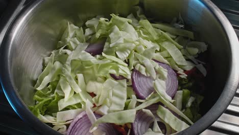 Close-up-chef-filling-a-bowl-with-vegetables-while-preparing-a-tuna-salad