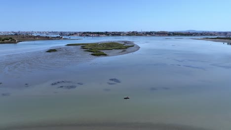 drone shot coming down over a shallow bay with small island