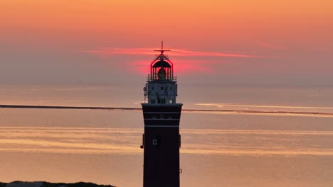 Vergrößerte-Aufnahme-Des-Westhoofd-Leuchtturms-Mit-Der-Sonne-Im-Hintergrund-Bei-Sonnenuntergang,-Luftaufnahme