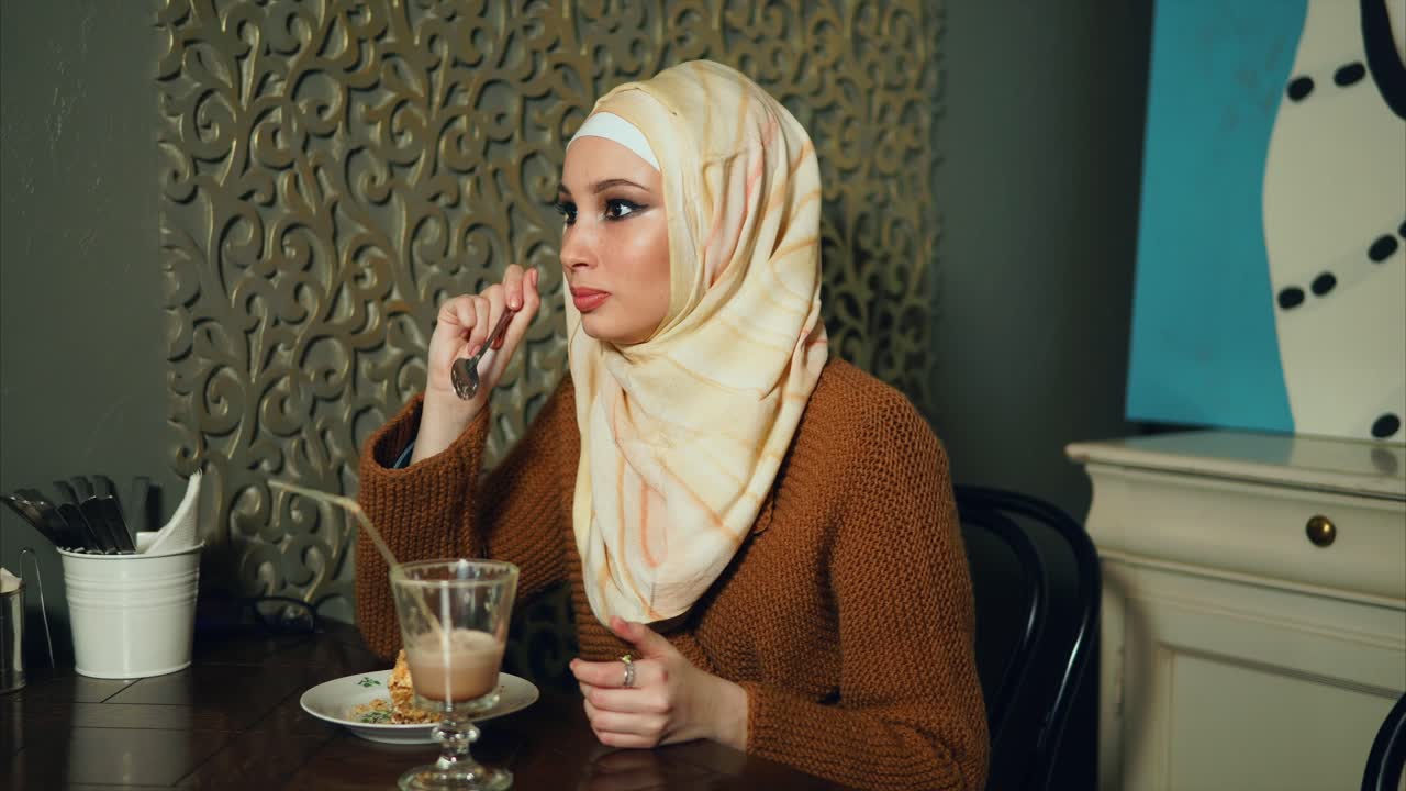 Woman in Hijab Enjoying Coffee and Dessert in a Cafe