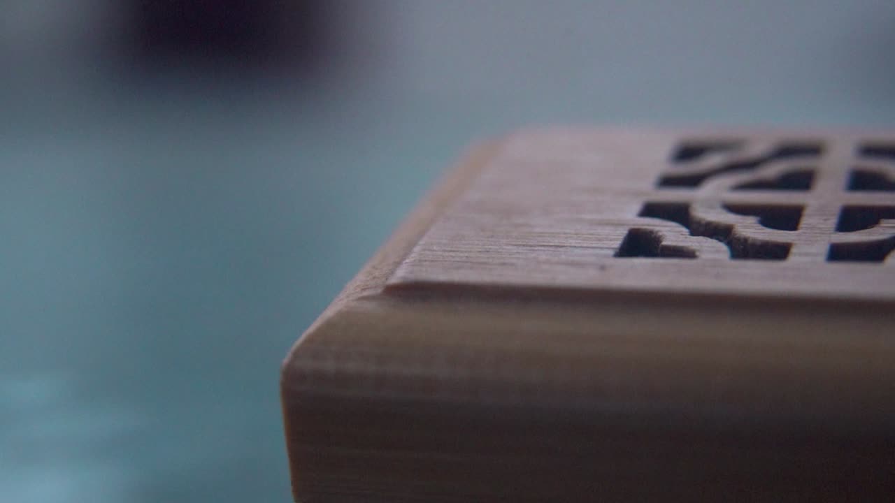 Et nærbillede makrooptagelse af rygende røgelse i en trækasse, spirituel rituel meditation, duftterapi, afslappende aromatisk hvid røg, tekstureret etui, cinematisk slow motion video 120 fps panorering til højre