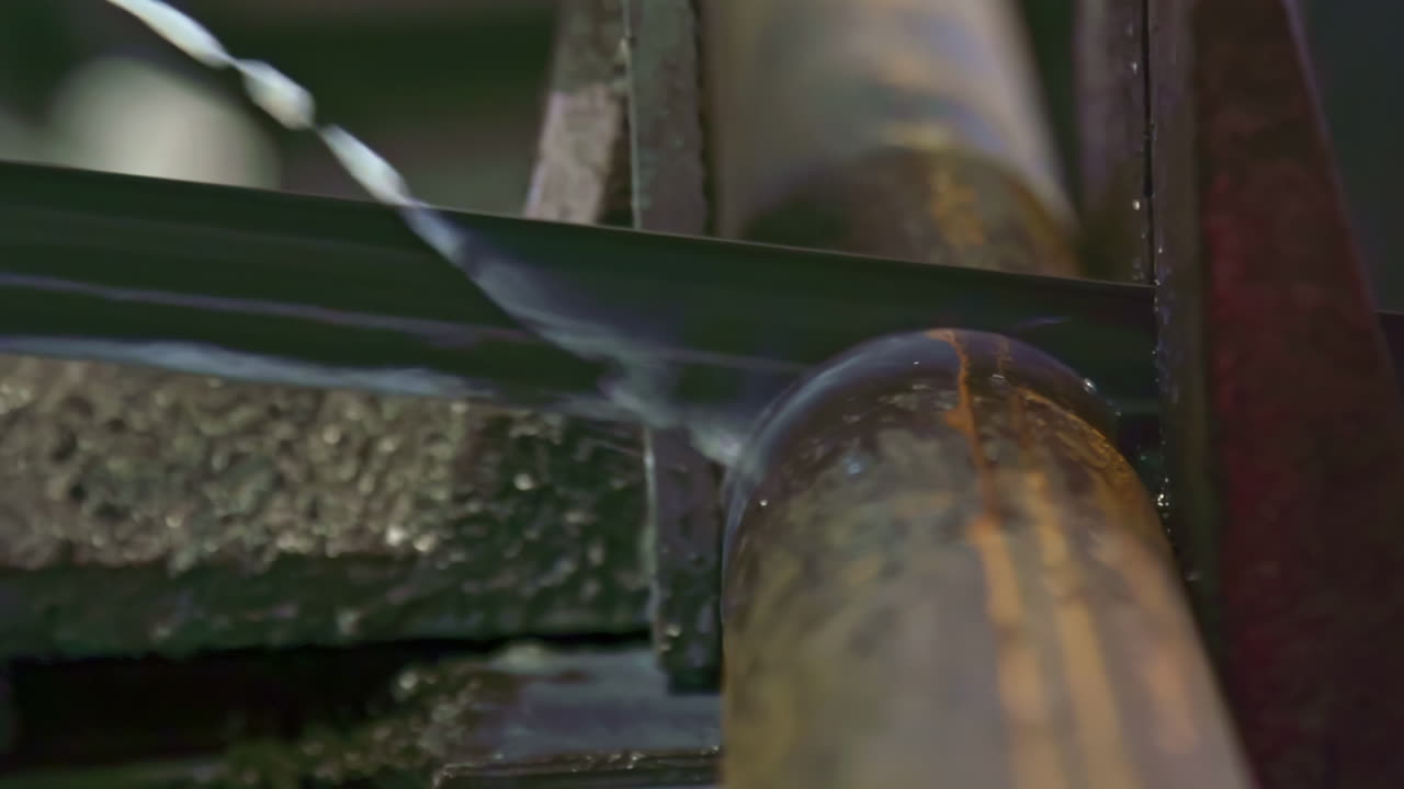 Industrial saw cutting a metal pipe with coolant
