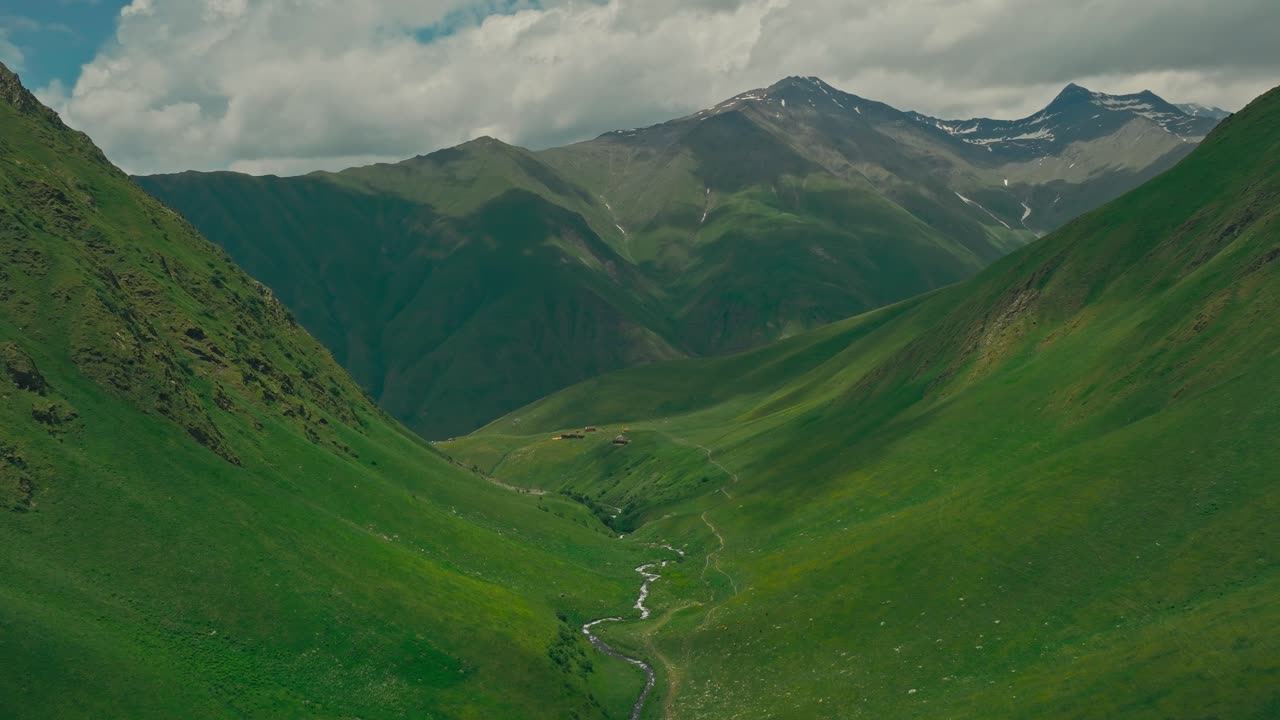 Lush green valley in Georgia's Juta, under dramatic sky, serene and vast