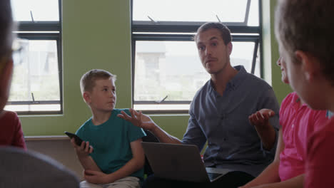 male teacher with laptop teaching in the class