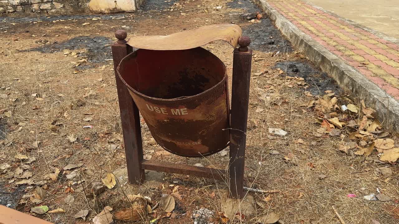 an unused rusty metal waste bin saying use me,