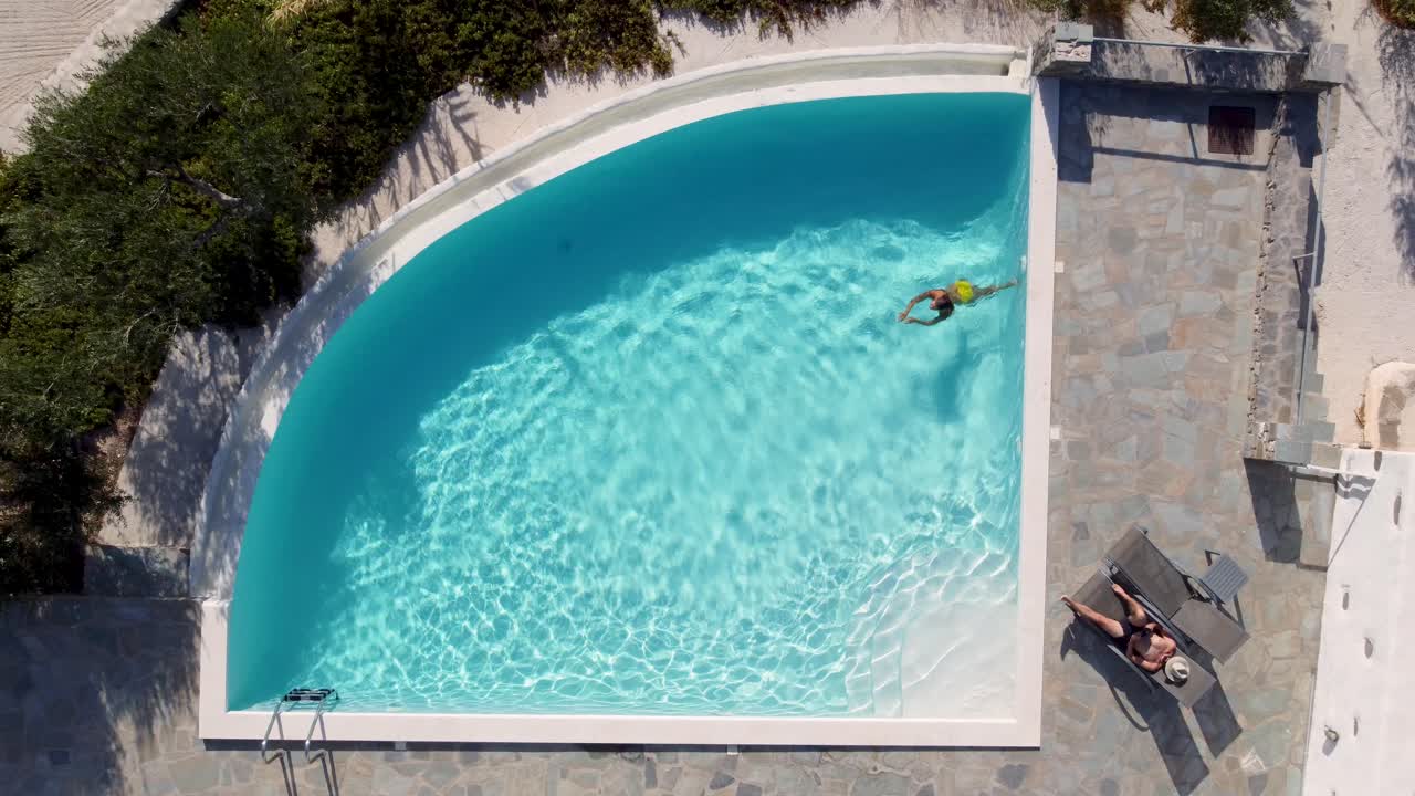 Luftfoto af et par, der slapper af ved en pool på en solrig dag