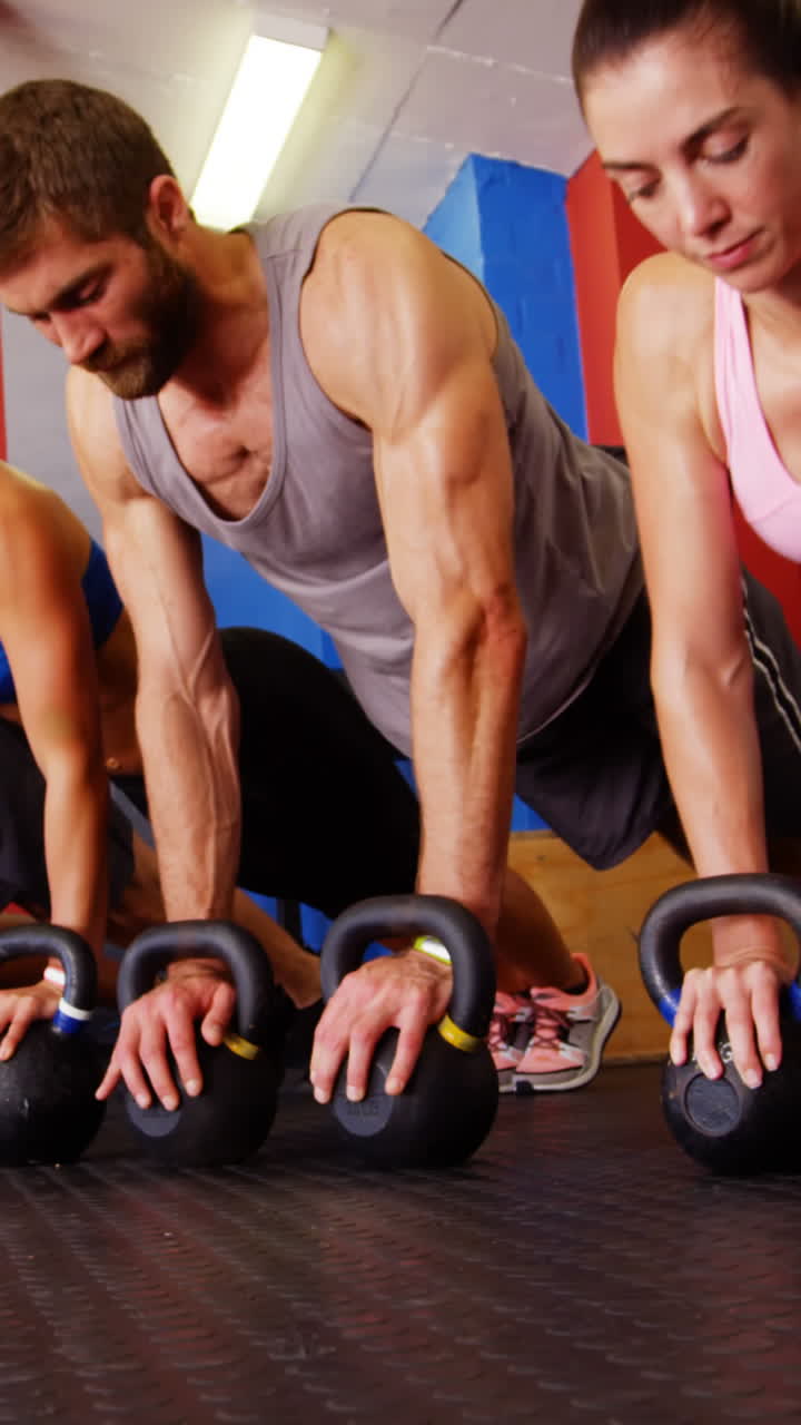 grupo de personas que realizan ejercicios de flexión con kettlebell