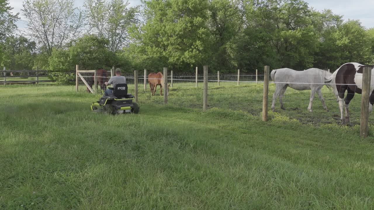 hombre montando una cortadora de césped eléctrica de giro cero cortando hierba en el rancho
