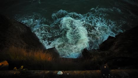 slow motion of rising tides at the base of a cliff at sunset