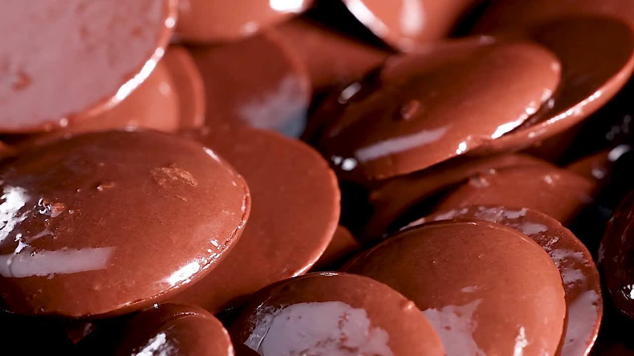 A detailed look at shiny chocolate discs with a smooth, reflective surface.