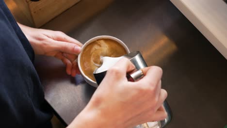 Barista-pours-freshly-steamed-milk-over-espresso-in-mug,-attempts-latte-art,-slow-motion-4K