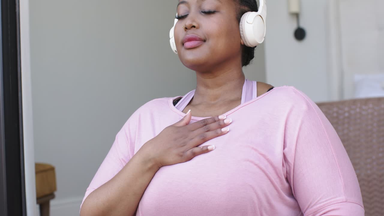 Dopo aver iniziato a respirare sul tappetino da yoga, la donna sta massaggiando l'addome e indossando le cuffie per concentrarsi meglio.