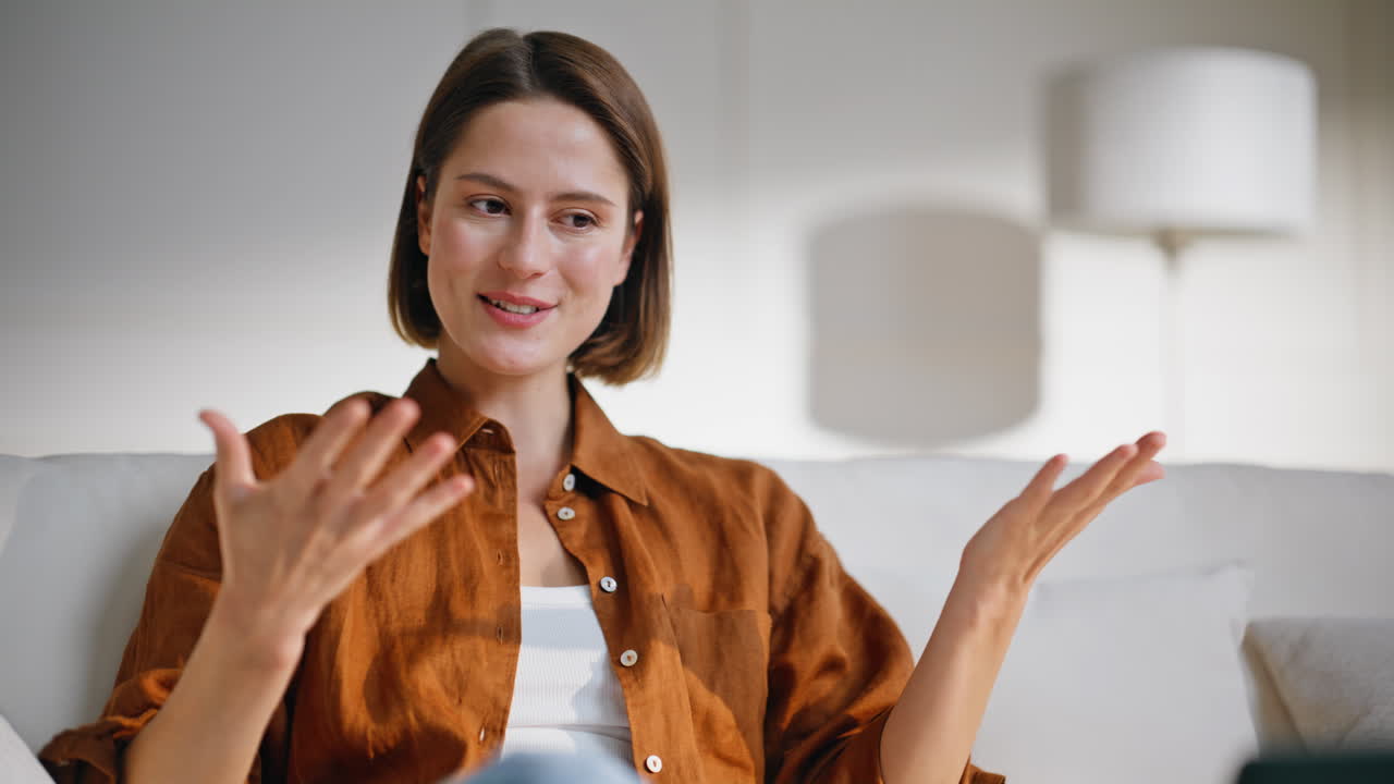 Girl speaking online conference sitting apartment sofa closeup. Smiling woman
