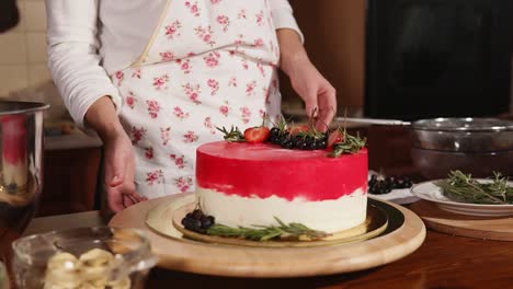 woman decorating a beautiful red and white layered cake with berries