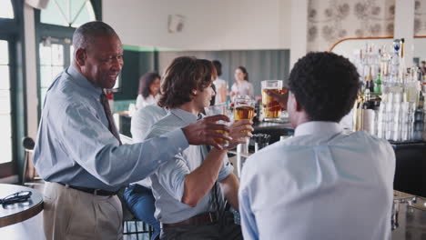 grupo de hombres de negocios celebrando con bebidas después del trabajo en un bar