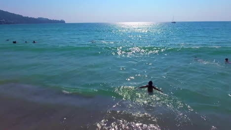 a low aerial view. a girl dives into the water while camera flies over her