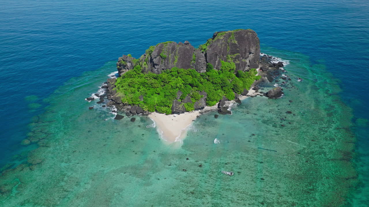 Isolated tropical island with vibrant reef ring in crystal clear blue water