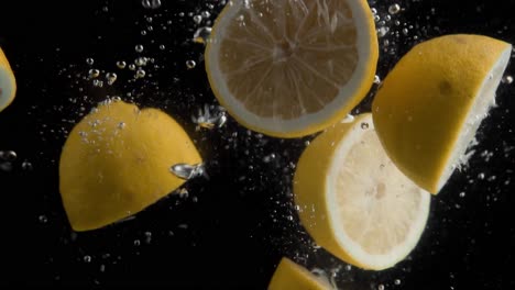 Limones-Cayendo-Al-Agua-En-Cámara-Superlenta,-Fondo-Negro,-Muchas-Burbujas-De-Aire,-4k240fps