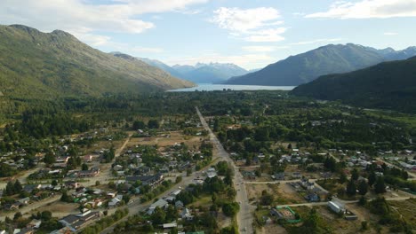 dolly in flying over lago puelo valley with a beautiful woodland, lake and andean mountains in background at sunset, chubut, patagonia argentina