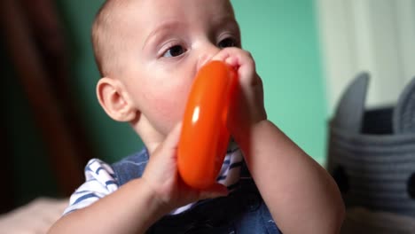 Primer-Plano-De-Un-Bebé-De-6-Meses-Masticando,-Dentición-Y-Engomado-En-Un-Juguete,-Jugando-En-La-Guardería