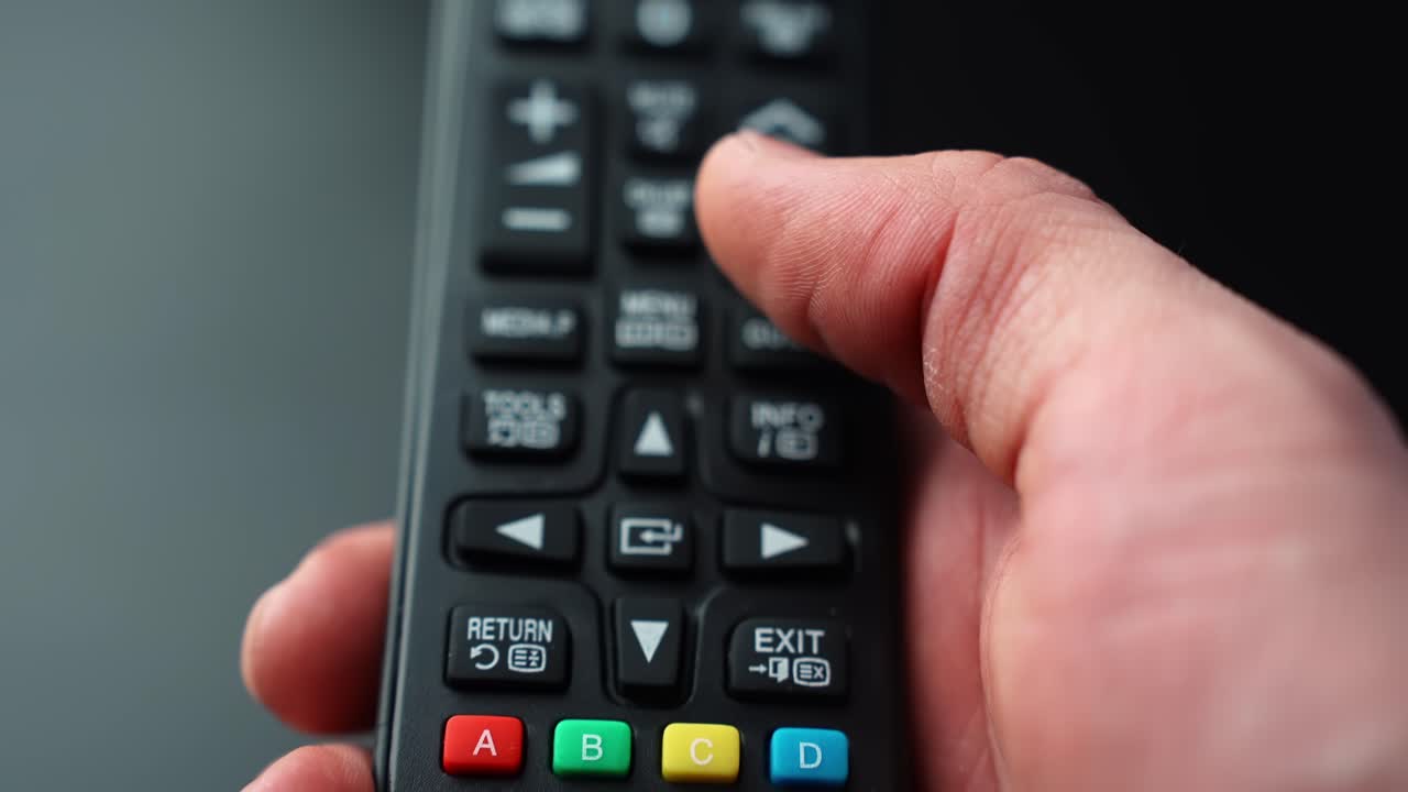 Close-up of a hand pressing the UP arrow on a TV remote control, navigating an on-screen menu with shallow depth of field for home entertainment tech b-roll