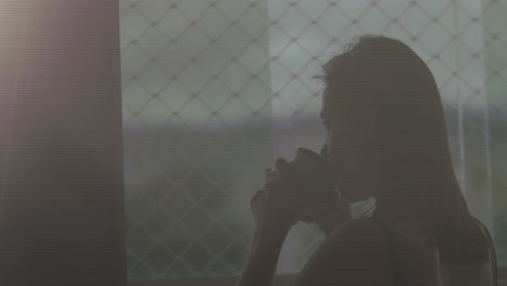 mujer morena de mediana edad bebiendo té por la noche mientras mira por la ventana, cámara lenta