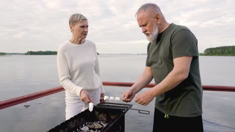 a couple of senior people roasting marshmallows over a barbecue