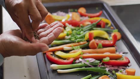 Mid section of asian senior woman sprinkling oregano over vegetable salad