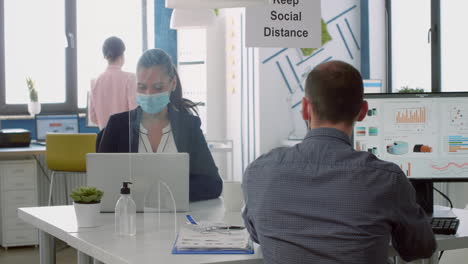 business team with face masks working in company office talking precaution to mantain safety measures