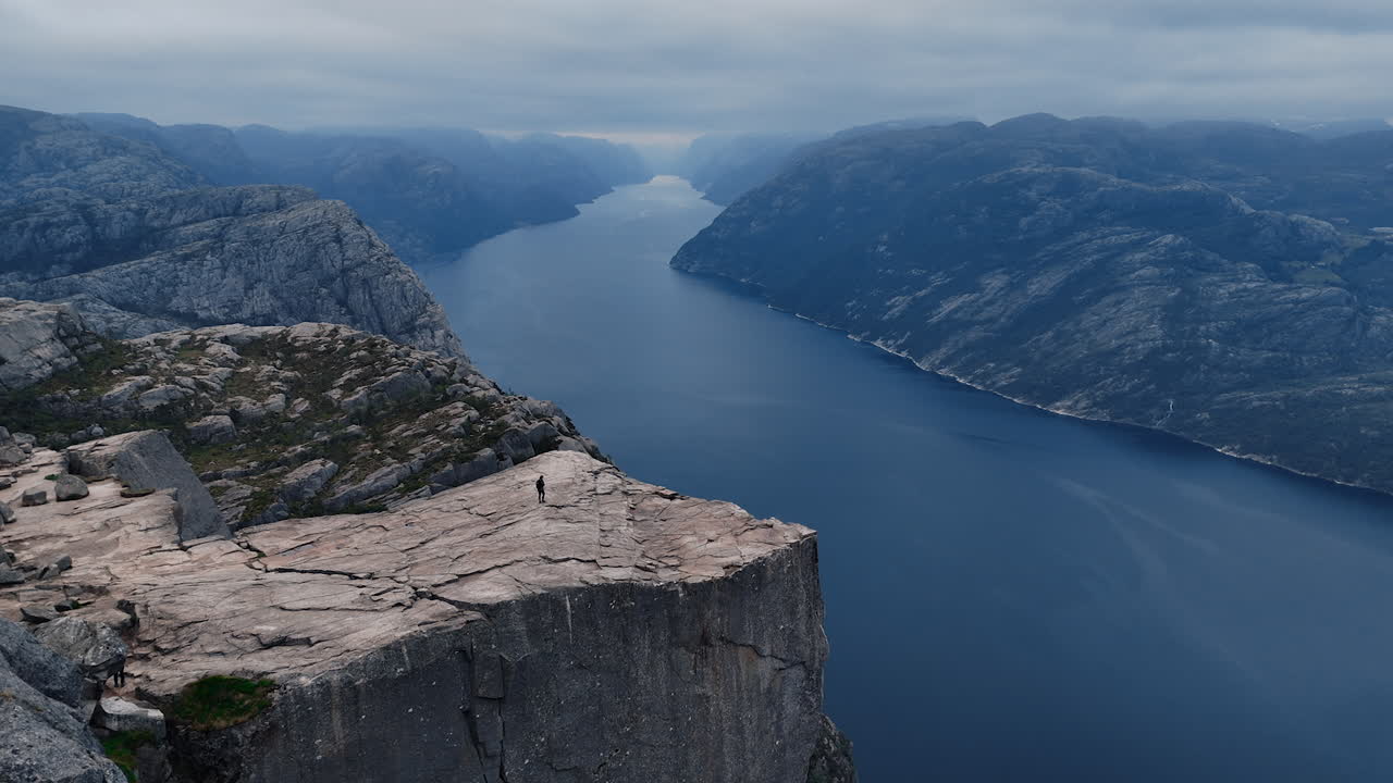 Person standing on Preikestolen (Pulpit Rock) overlooking Lysefjord