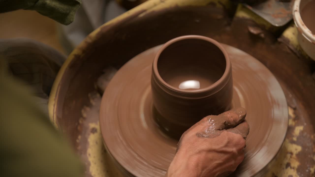 Primo piano di mani maschili che creano una ciotola di argilla su un tornio da vasaio. Artigianato e produzione di esclusive stoviglie da tè in argilla