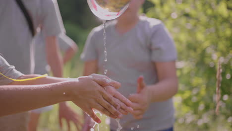 children wash their hands with water in the forest on a hike. hand hygiene on the street on a hike and in nature