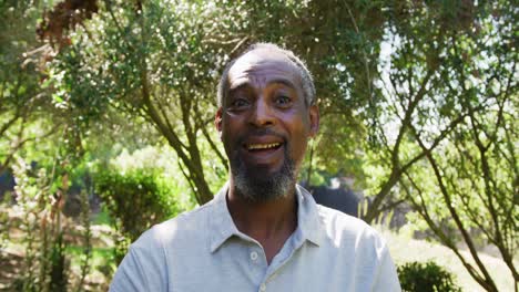 Portrait-of-senior-african-american-man-smiling-in-a-sunny-garden