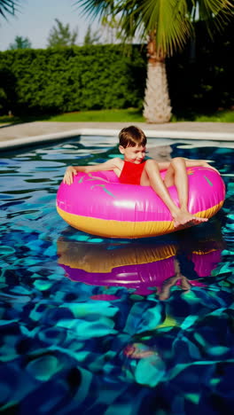 a young boy enjoys a sunny day in a swimming pool with a donut inflatable float