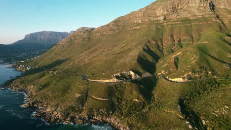 chapmans peak road coastline during sunset with table mountain in background, aerial