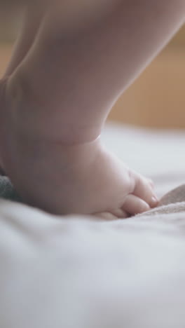 adorable infant boy little legs like toys stand on muslin swaddle on changing table extreme close view