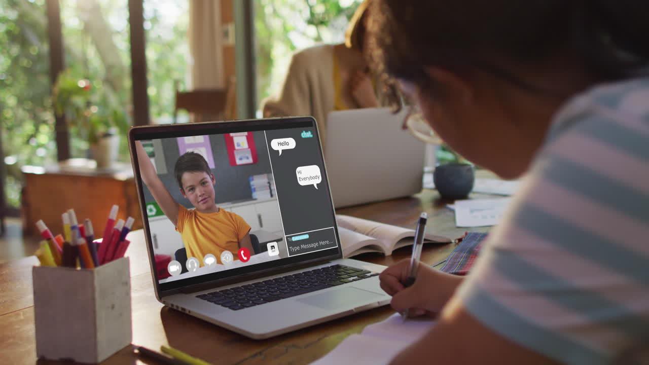 Composite video of girl using laptop for online lesson at home, with boy raising hand on screen