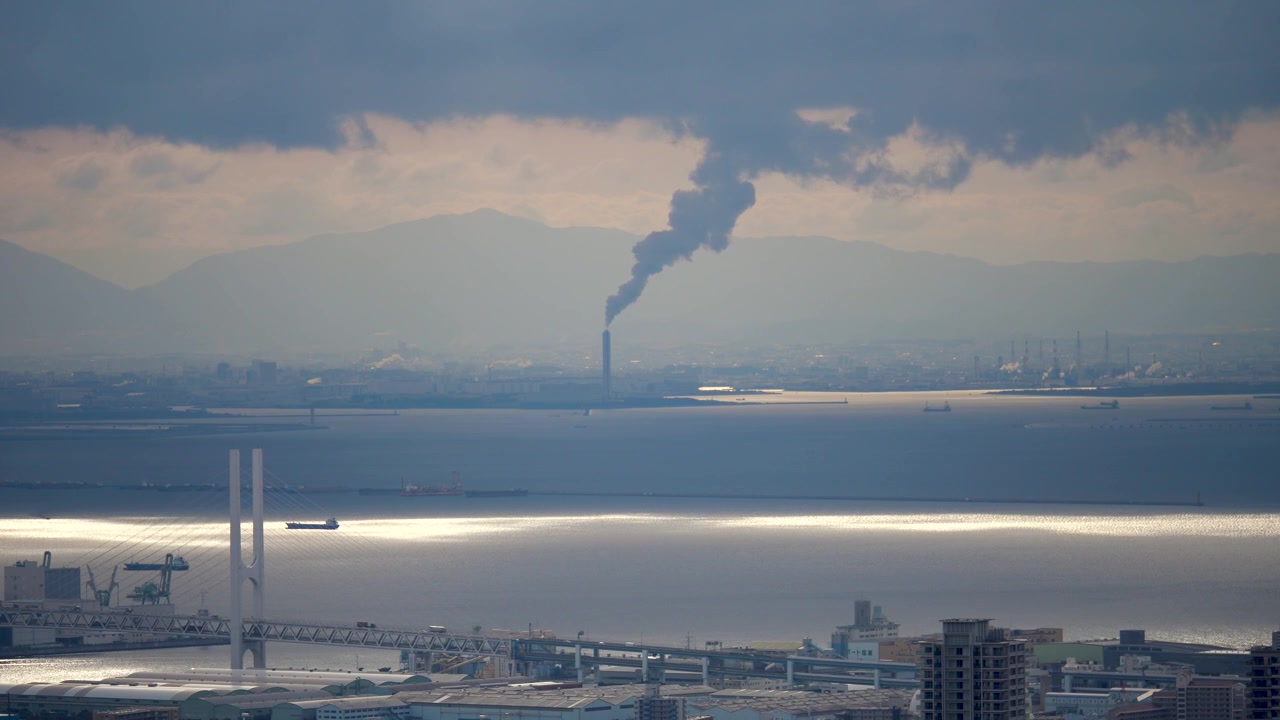 海沿いの都市のスカイライン、工業用の煙突と近代的な橋。