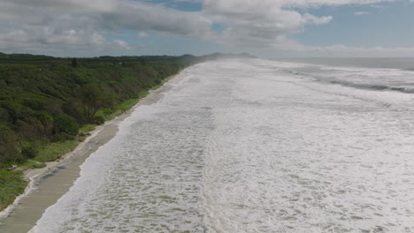 4K-Aerial-wide-moving-shot-of-Australian-Beach-with-Sea-Foam,-ocean-foam,-beach-foam,-or-spume-created-by-the-agitation-of-seawater