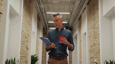 business man walking towards the camera in a corridor. mature male go to a work meeting.