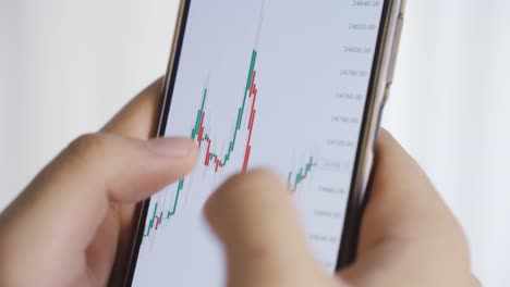 Close-up-of-male-hands-looking-and-analyzing-fluctuating-stock-market-chart.